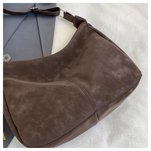 Detail of dark brown tote bag with reinforced stitching and silver metallic buckle