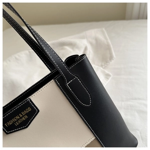 Close-up of contrast stitching and gold fashion leather tag on bicolor tote bag