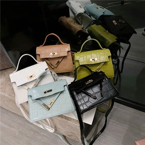 Flat lay showing trapezoidal crocodile pattern handbags with metal twist locks and handles