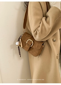 Detail of dark brown frosted leather shoulder bag with gold buckle and sports charm