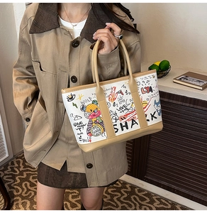 Detailed close-up of graffiti bear prints and leather trim on the bucket tote bag