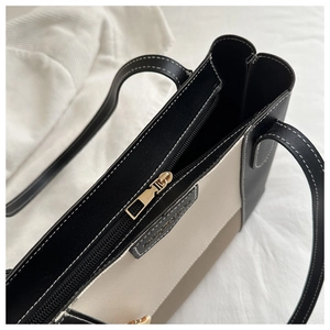 Detail of metal zipper closure and tricolor leather stitching on large tote bag