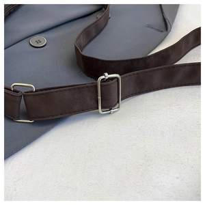 Detail of adjustable dark brown suede shoulder strap with silver metal buckle on a blue tote