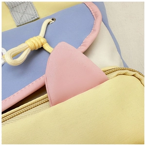 Detail of pink cat ear decoration and drawstring on a colorful canvas tote bag
