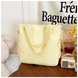 Detail of cream yellow large capacity tote bag with drawstring side pockets and adjustable strap
