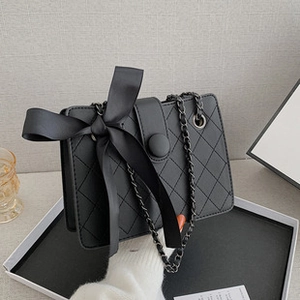 Close-up of black quilted PU leather bucket bag featuring a large decorative silk bow