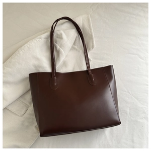 Detailed top view of a minimalist large dark brown tote bag on soft textured fabric