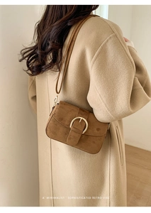Detailed macro view of the vintage brown suede texture and large golden buckle on the bag