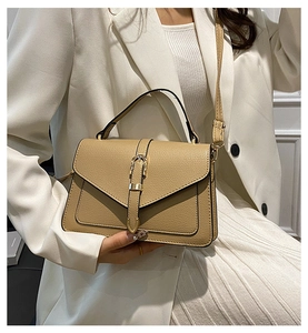 Close-up of vintage tan leather crossbody bag with gold buckle and top handle detail