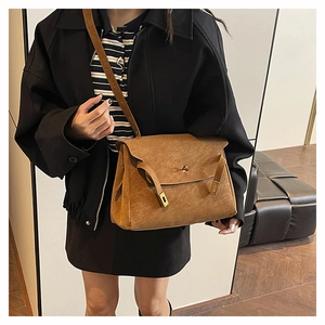 Detail of vintage brown leather handbag featuring a classic metal turn-lock closure