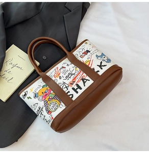 Détail du sac seau en toile avec imprimés graffitis et poignées en cuir marron