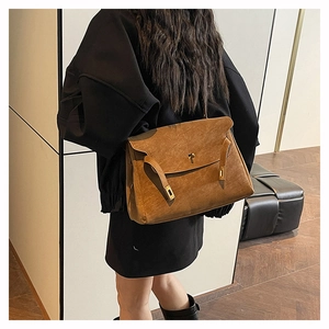 Close-up of vintage brown suede tote bag with golden metal buckle and leather straps