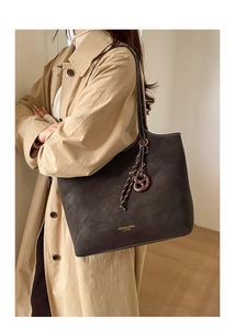 Gros plan sur un cabas vintage en cuir mat avec lettrage doré et charme de nœud