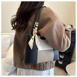 Detail of color-block tote bag with silk scarf accessory and brand leather patch