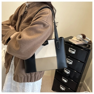 Detail of color-block tote bag with white contrast stitching and slim leather straps