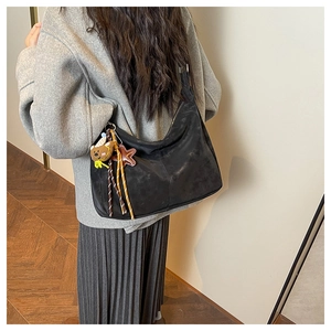 Close-up of black matte shoulder bag with cute bear charm and star keychain detail