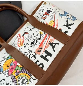 Gros plan sur les imprimés graffiti du sac fourre-tout en toile avec finitions en cuir