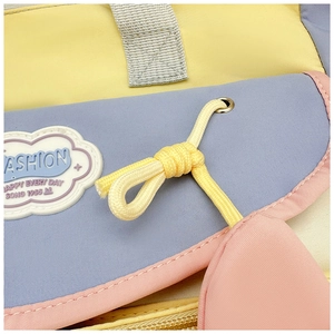 Detail of macaron patchwork bag with cloud badge and yellow braided knot decor
