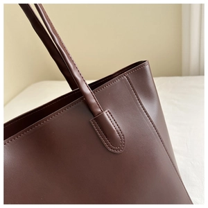 Close-up of dark brown tote bag showing reinforced stitching and matte leather texture