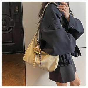 Chic beige shoulder bag featuring a brown teddy bear charm and stylish tassel detail