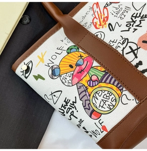 Détail du sac seau en toile avec ours graffiti coloré et poignée en cuir marron