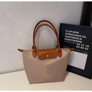 Close-up of khaki nylon tote bag with brown leather flap and gold metal snap button