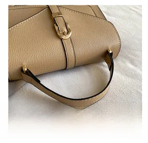 Detail of khaki textured leather handbag featuring a gold metal buckle and sturdy handle