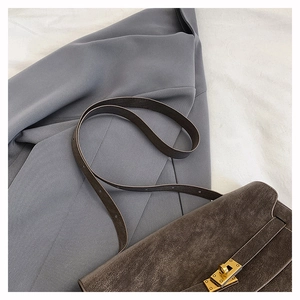 Detail view of charcoal leather texture and gold twist-lock closure on tote bag