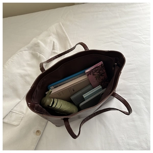 Top-down view of a spacious brown tote bag holding a tablet, umbrella, and essentials