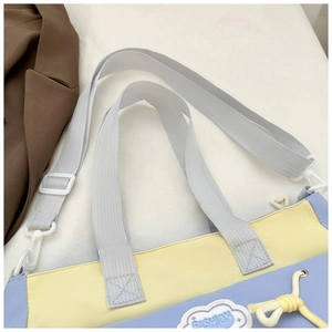 Detail of color-block tote bag featuring cloud patch, fashion text and purple strap