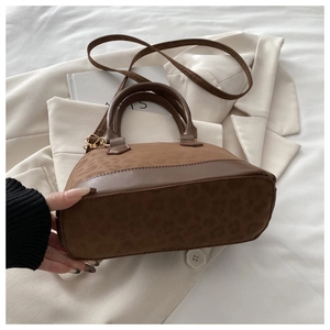 Detail of vintage shell handbag showing leopard print suede texture and solid brown trim