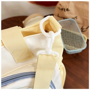 Close-up of yellow woven strap and blue zipper detail on contrast shoulder bag