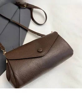 Detail view of dark brown vintage faux leather shoulder bag with circular buckle and strap