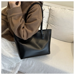 Close-up of a large black leather tote bag worn over the shoulder for a stylish look