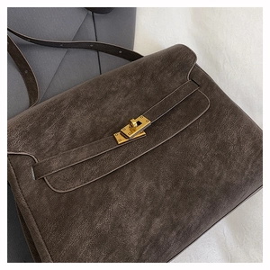 Close-up of vintage dark brown leather briefcase with golden turn-lock and leather strap