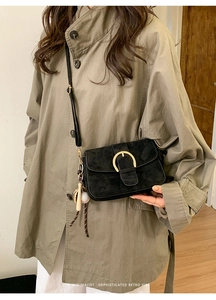 Minimalist black suede crossbody bag with gold buckle and baseball charm detail