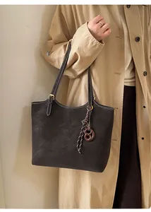 Detail of dark brown leather tote bag with gold lettering and decorative knot strap