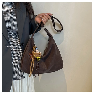 Detail of a brown vintage hobo bag with a cute bear pendant and adjustable strap