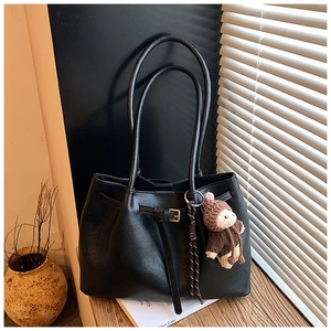 Detail der schwarzen Tote-Bag aus Kunstleder mit Litschi-Struktur und Bärenanhänger
