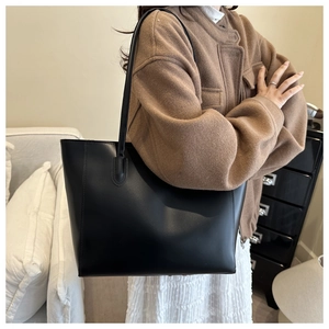 Dettaglio di una grande borsa tote vintage nera su una modella in una stanza minimalista