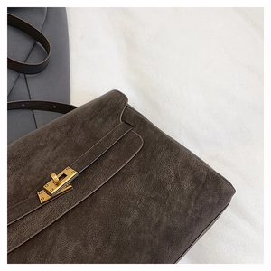 Detailed close-up of dark brown vintage leather texture and golden metal twist lock on tote