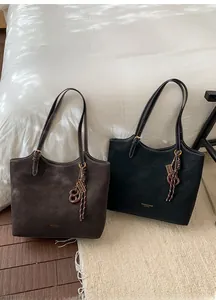 Detail view of vintage tote bags in coffee and black with decorative metal keychains