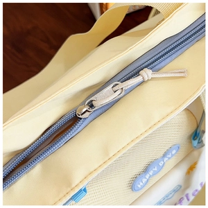 Close-up of yellow tote bag silver zipper and Happy Days blue rubber patch logo