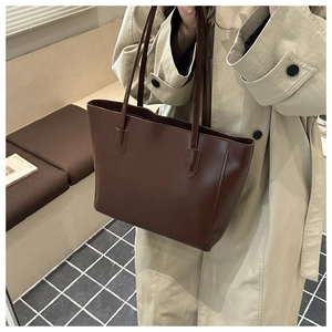 Detailed view of deep brown leather tote bag on model shoulder in warm lifestyle setting