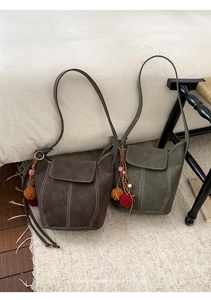 Close-up of matte faux leather crossbody bags in dark coffee and green with tassel details