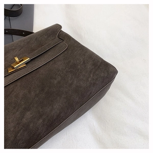 Detail of dark brown lychee leather texture and golden metal twist lock on tote bag