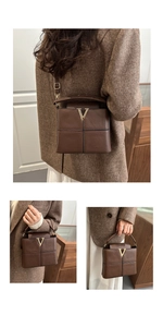 Detail der dunkelbraunen Leder-Eimertasche mit goldenem V-Logo und Umhängeriemen