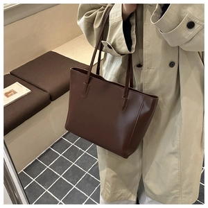 Grande borsa tote marrone scuro con manici lunghi su una panca di legno