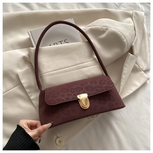 Detail of burgundy leopard embossed shoulder bag with gold clasp on white blazer