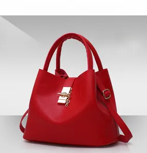 Macro detail of red lychee textured PU leather bucket bag with gold clasp and chain charm